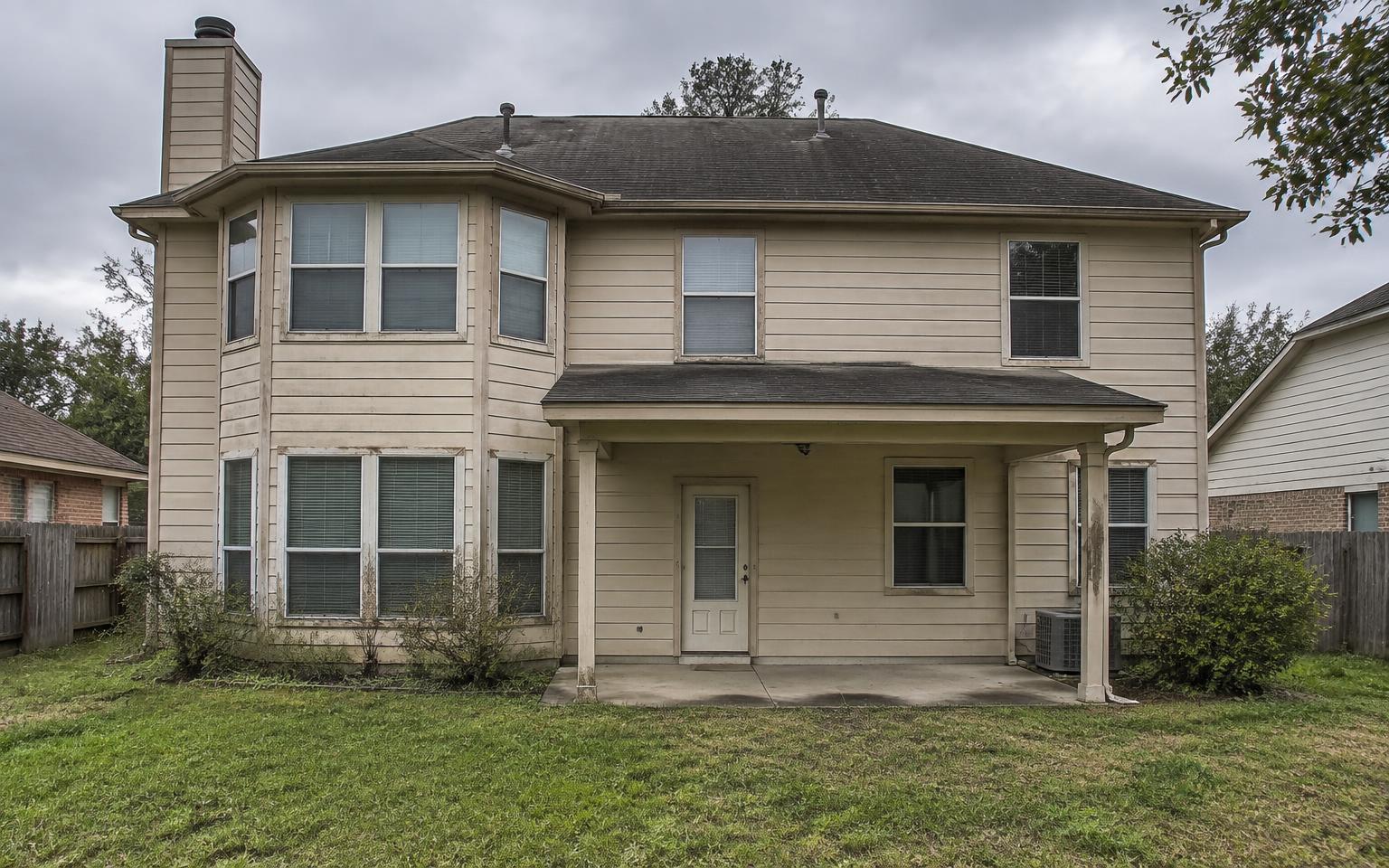 Aging home exterior before renovation with faded siding, weathered trim, and sparse landscaping