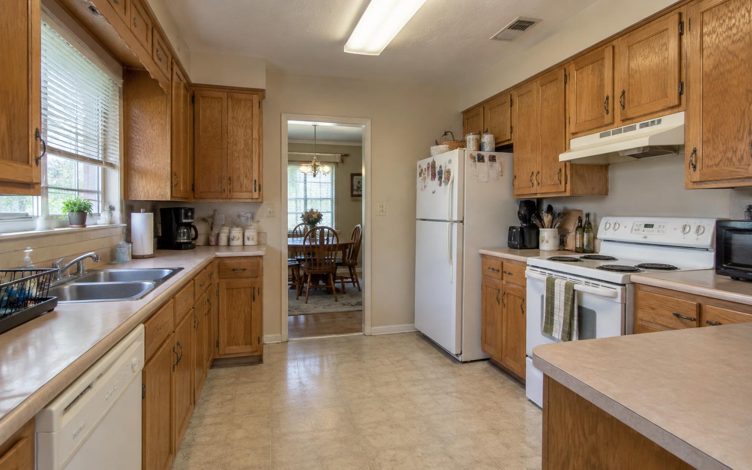 Dated kitchen before renovation with honey-oak cabinets, laminate counters, and white appliances